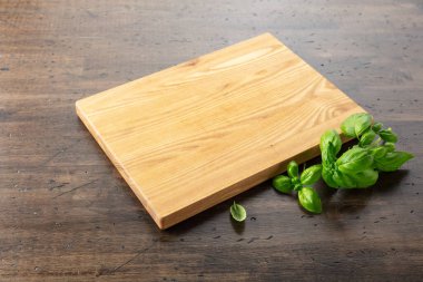 Tahta ve fesleğeni eski ahşap mutfak masasında kesiyorum. Mutfak geçmişi. Boş tahta kesme tahtası, ürün görüntüleme alanı.