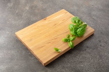 Mutfak masasında tahta ve fesleğen kesiyorum. Mutfak geçmişi. Boş tahta kesme tahtası, ürün görüntüleme alanı.