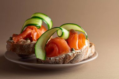 Açık sandviçler, füme fileto, krem peynir, salatalık ve bej kapari. Boşluğu kopyala.