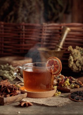 Bir fincan bitkisel çay, çeşitli kurutulmuş bitkiler, çiçekler ve baharatlar. İçindekilerle çay ve kurutulmuş portakal dilimleri..