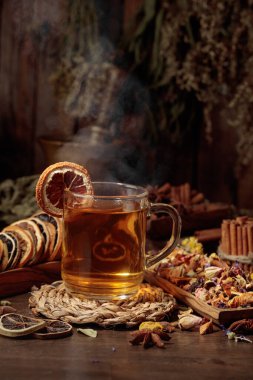 Bir fincan bitkisel çay, çeşitli kurutulmuş bitkiler, çiçekler ve baharatlar. İçindekilerle çay ve kurutulmuş narenciye..