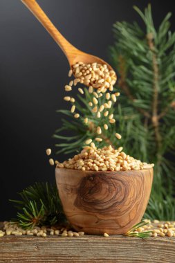 Çam fıstıkları ahşap bir kaseye dökülür. Soyulmuş çam fıstığı ve sedir dalı eski bir ahşap masada. Boşluğu kopyala.