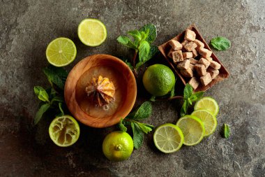 Tahta narenciye sıkacağı ve yaz ferahlatıcı içecekler yapmak için malzemeler. Esmer şeker, limon ve taş bir masada taze nane dalları. Üst görünüm.
