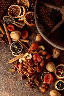 Kahverengi bir arka planda kurumuş meyve ve fındık. Kurutulmuş turunçgiller, kayısılar, kuru üzümler, çeşitli fındıklar ve baharatlar. Üst görünüm.