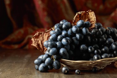 Eski ahşap bir masada bir demet mavi üzüm.