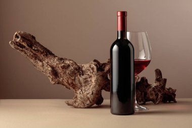 Bej arka planda yıpranmış eski bir pürüz olan bir şişe ve bir bardak kırmızı şarap. Kopyalama alanı ile ön görünüm.