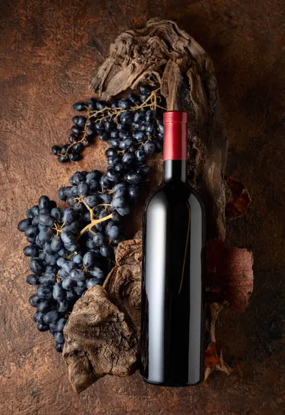 Bir şişe kırmızı şarap, mavi üzümler ve yıpranmış eski parçalar. Etiketini şişenin üzerine koy..