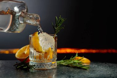 Limon ve biberiyeli cin tonik kokteyli. İçki şişeden buzlu bir bardağa dökülür. Boşluğu kopyala.