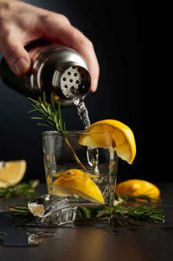 Limonlu ve biberiyeli kokteyl Cin ve Tonik. Barmen bardaktan bardağa kokteyl doldurur..