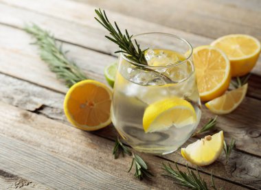 Buzlu sert maden suyu, biberiye ve buzlu bardakta limon dilimleri. Eski ahşap bir masanın üzerinde malzemeleri olan kokteyl. Boşluğu kopyala.