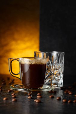 Espresso, bir bardak soğuk su ve siyah taş bir masada kavrulmuş kahve çekirdekleri. Boşluğu kopyala.