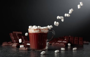 Cam bardakta mini marşmelovlu sıcak çikolata. Kırık bir arka planda acı çikolata.