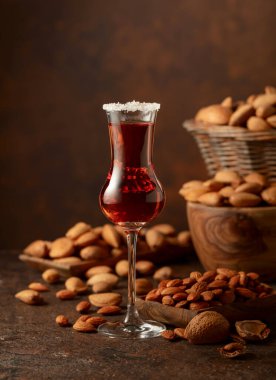 Alkolik İtalyan likörü Amaretto. Şarap masasında badem fıstığı var. Boşluğu kopyala.