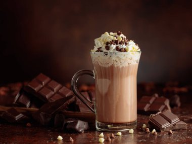 Krem şantili sıcak çikolata içeceği. Cam bardakta kakao ve koyu kahverengi arka planda acı çikolata..