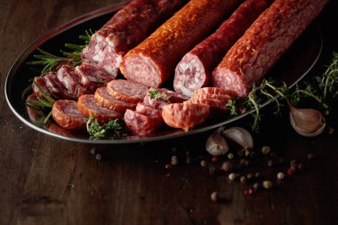 Kurutulmuş sosis, biber, kekik, biberiye ve eski ahşap bir masada sarımsak..