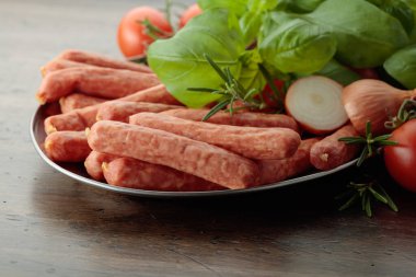 Eski ahşap bir masada fesleğen ve domatesli sosisler..