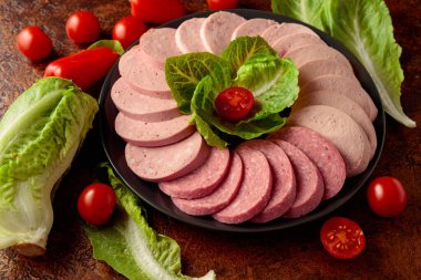 Kahverengi bir arka planda yeşil ve sebzeli çeşitli haşlanmış sosisler..