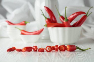 Beyaz ahşap bir masada yeşil saplı taze kırmızı biber. Seçici odak.