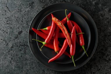 Siyah taş bir masada yeşil saplı taze kırmızı biber. Üst görünüm, alanı kopyala.