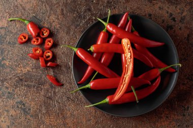 Kahverengi bir arka planda yeşil saplı taze kırmızı biber. Üst görünüm, alanı kopyala.