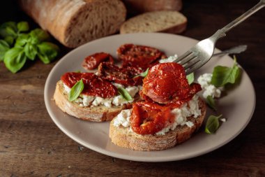 Ciabatta, zeytinyağı, ricotta ve fesleğende kurutulmuş domates. Eski ahşap bir masada geleneksel İtalyan atıştırması..
