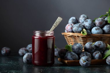 Lacivert arka planda erik reçeli ve taze böğürtlen. Mutfak masasında reçelli olgun erikler..