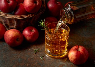 Apple kombucha şişeden bardağa dökülür. Bir bardak kombu çayı ve taze elmalar eski bir mutfak masasında oturur..