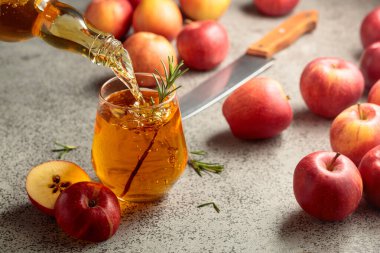 Elma şarabı şişeden bardağa dökülür. Eski bir mutfak masasında elmalı taze içecek..