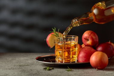 Apple kombucha şişeden bardağa dökülür. Eski bir mutfak masasında elmalı taze içecek. Boşluğu kopyala.