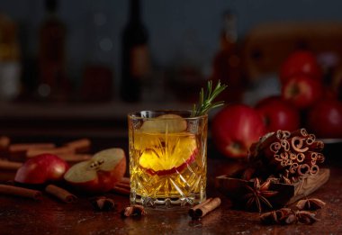 Elma dilimleri ve biberiye filizi ile elmalı kombu çayı. Taze elmalar, tarçın çubukları ve anason eski bir mutfak masasına saçılmış..