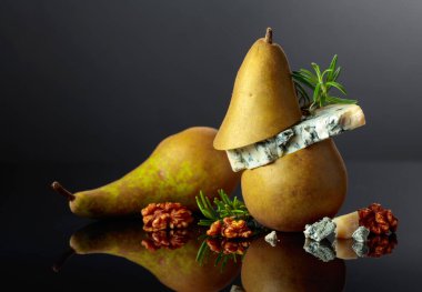 Armut, ceviz ve biberiyeli mavi peynir. Siyah yansıtıcı arka planda küflü peynir. Boşluğu kopyala.