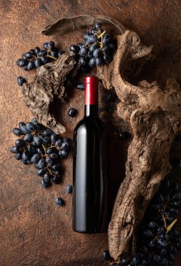 Bir şişe kırmızı şarap, mavi üzümler ve yıpranmış eski parçalar. Etiketini şişenin üzerine koy..
