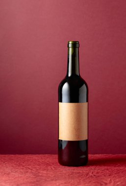 Kırmızı arka planda bir şişe kırmızı şarap. Boşluğu kopyala.