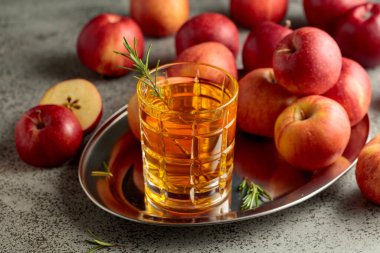 Elma suyu ve taze elmalar eski bir mutfak masasında..