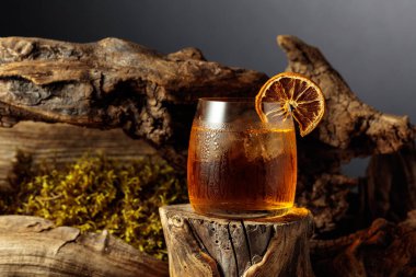 Eski moda bir karışım, buz ve kurutulmuş portakal dilimi ile eski ahşap bir kütükte.. 