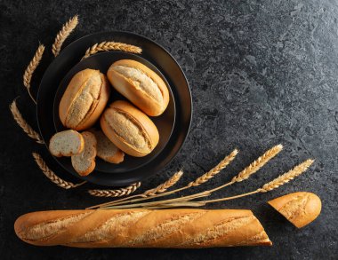 Ekmek, Fransız çöreği ve siyah taş bir masada buğday kulağı. Üst Manzara. Boşluğu kopyala.