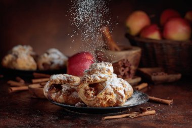 Elma ve tarçınlı ev yapımı mini elmalı turtalar. Üzerine pudra şekeri serpiştirilmiş taze pişmiş yiyecekler. Viyana pastası.
