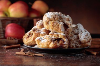 Elma ve tarçınlı ev yapımı mini elmalı turtalar. Üzerine pudra şekeri serpiştirilmiş taze pişmiş yiyecekler. Viyana pastası.
