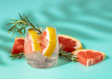 Buzlu, greyfurtlu ve biberiyeli yaz içeceği. Soğuk, gevrek ve yeşil bir arka planda palmiye gölgeleri tarafından öpülmüş. Boşluğu kopyala.