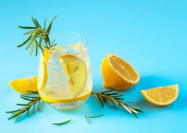 Buzlu, limonlu ve biberiyeli yaz ferahlatıcı içecek. Kopyalama alanı olan mavi arkaplan.