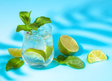 Buzlu, limonlu ve naneli yaz ferahlatıcı içecek. Kopyalama alanı olan mavi arkaplan.