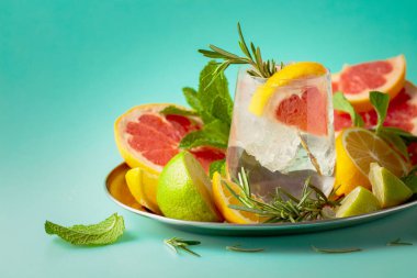 Buz, narenciye, biberiye ve naneli ferahlatıcı bir yaz içeceği. Kopyalama alanı olan yeşil arkaplan.