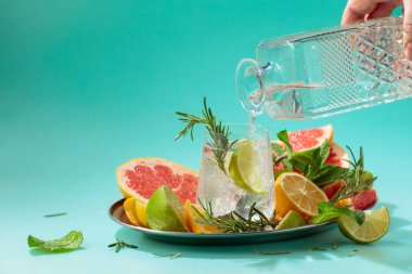 Buzlu, narenciyeli, biberiyeli ve naneli kokteyl. Sert alkol bir sürahide bardağa dökülür. Kopyalama alanı olan yeşil arkaplan.