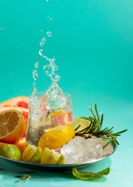 Buz, narenciye, biberiye ve naneli ferahlatıcı bir yaz içeceği. Limon dilimi bardağa düşer. Boşluğu kopyala.