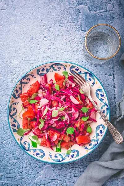 Winter salad - pickled red cabbage salad with radish, tomatoes, onion and  winter purslane. Vegetarian healthy food.