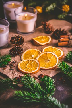 Kurumuş portakal ve Noel baharatları, noel ağacı dalları, tarçın, mutfak masasında mumlar.