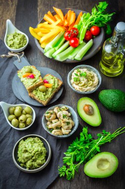 Taze meyve suyu, avokado sosu, humus ve marine edilmiş mantarlı vejetaryen çiğ yiyecekler.