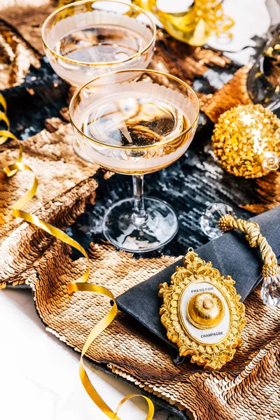 Two glasses of sparkling wine on festive table for New Year, party or carnival.  Bell push button for champagne, in golden tone