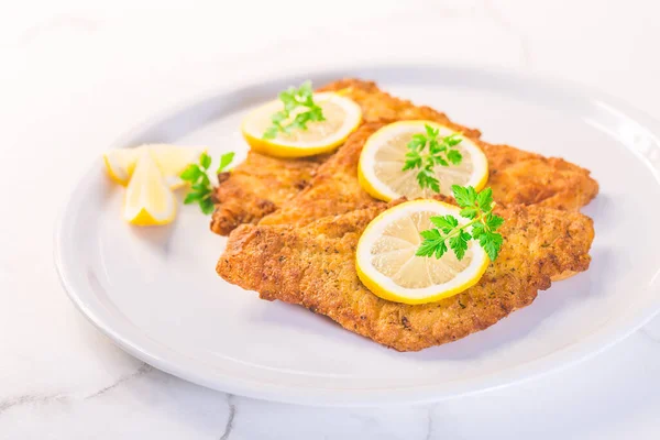 Breaded fish, baked and served with lemon. Common dab, edible flatfisch (Limanda limanda)