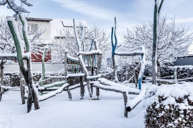 Empty public playground Empty public playground covered by fresh snow with play equipments made from wood